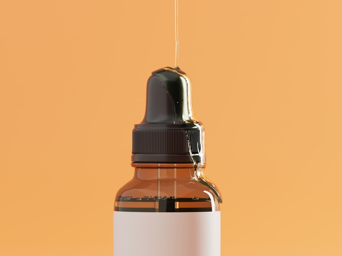 Ảnh minh hoạ — lọ serum nhỏ giọt phong cách biên tập, nền cam ấm