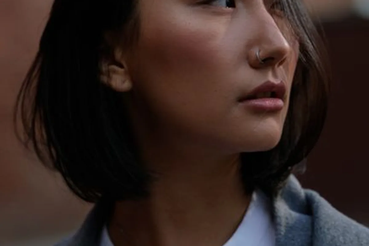 Illustrative image — An Asian woman with a bob and natural skin, in a white top and grey coat