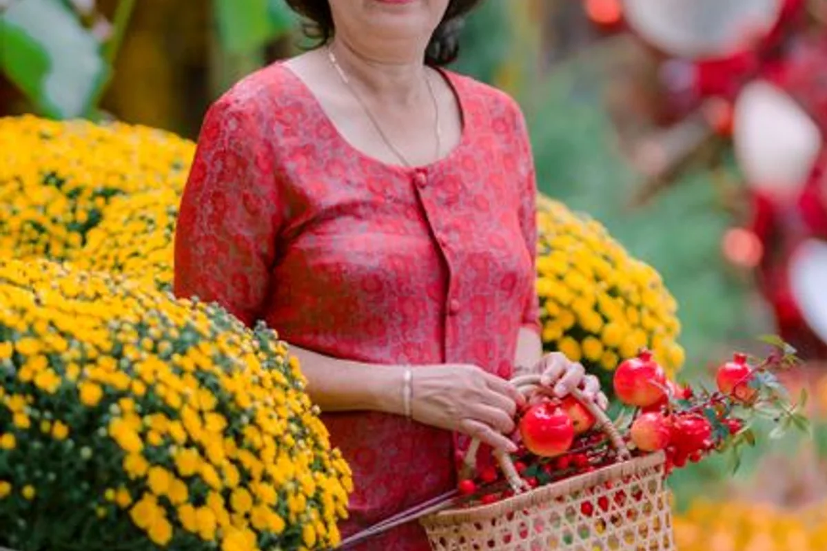 Ảnh minh hoạ — Phụ nữ trung niên áo bà ba đỏ cầm giỏ hoa cúc vàng ngày Tết, gương mặt phúc hậu