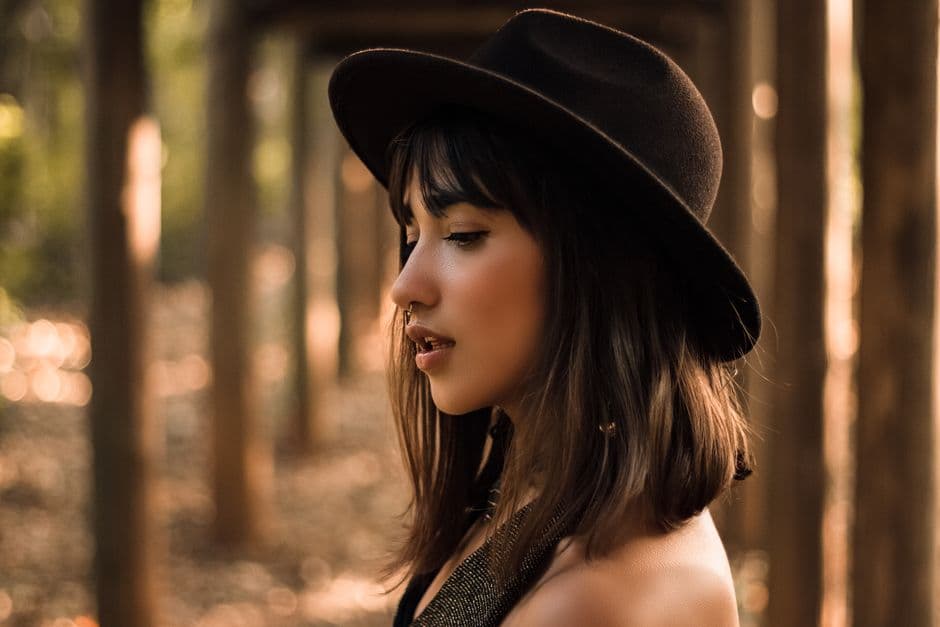 Ảnh minh hoạ — Profile portrait of a woman in a hat with bokeh background outdoors.
