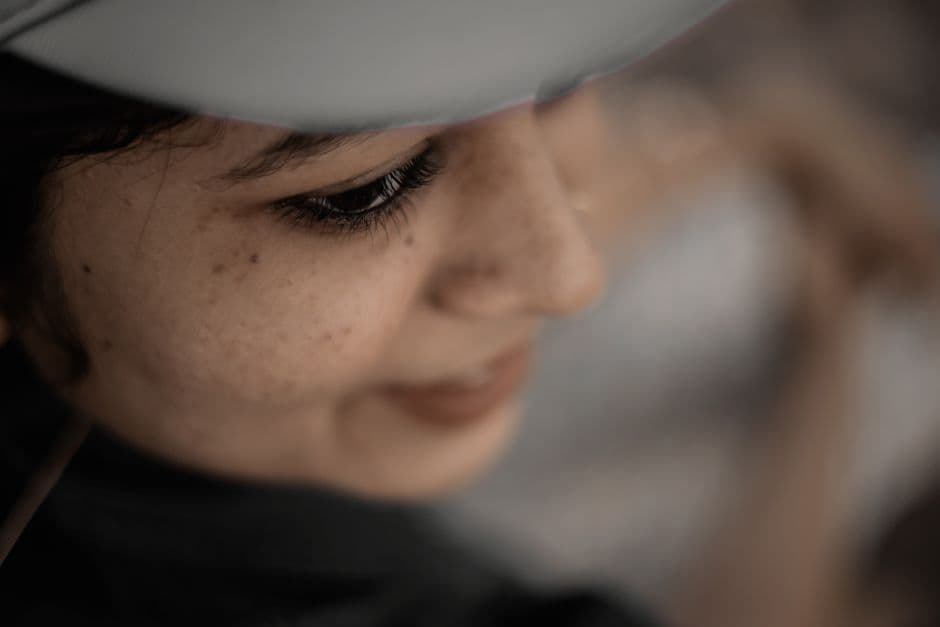 Иллюстрация — Artistic close-up shot of a woman wearing a cap, with a soft focus and blurred background.