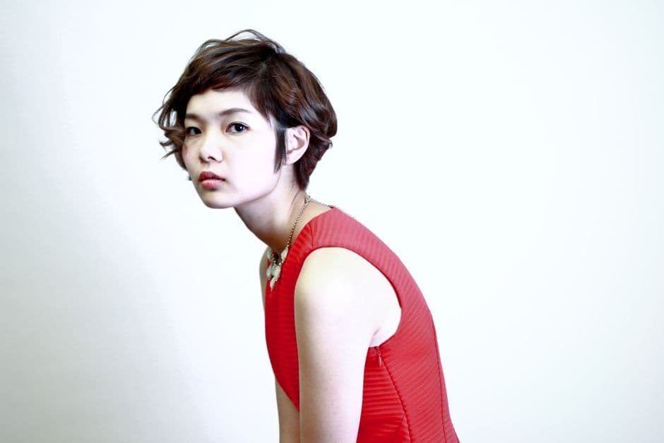 Ảnh minh hoạ — Elegant portrait showcasing a young woman with short hair in a vibrant red dress, exuding modern fashion.