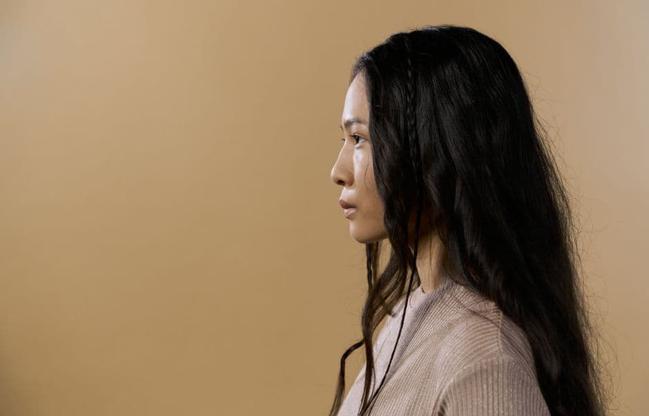 Ảnh minh hoạ — A side profile portrait of a woman in a sweater against a neutral beige background.