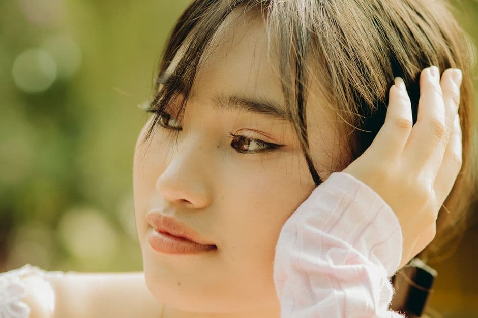 Ảnh minh hoạ — Close-up of a pensive young woman with natural lighting and soft focus outdoors.