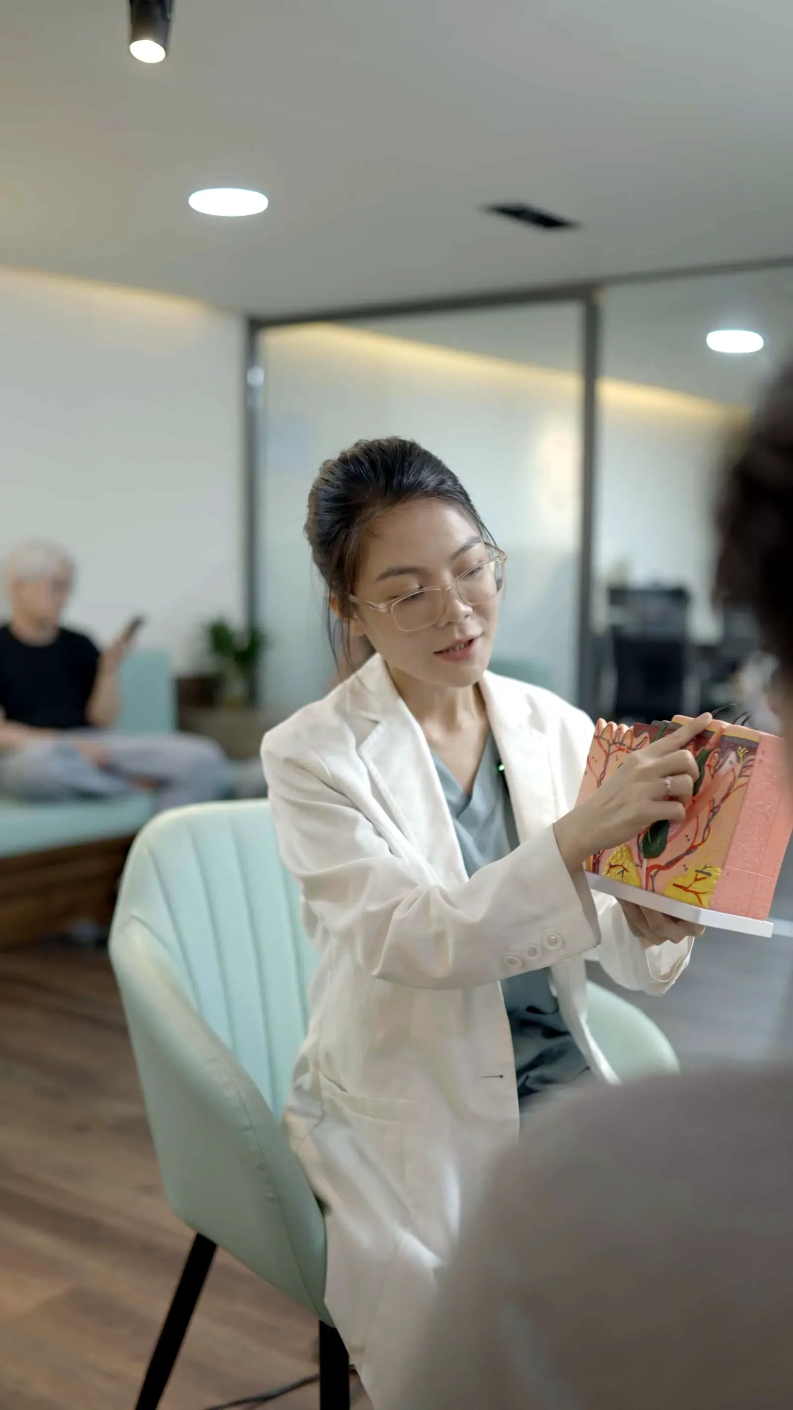 Dr. Kim Kha explaining on a skin model