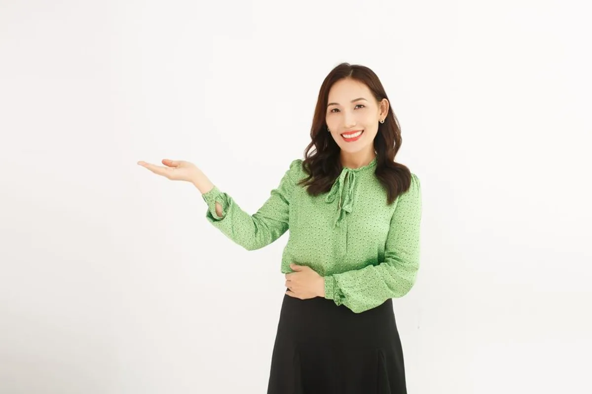 Ảnh minh hoạ — Phụ nữ châu Á nụ cười cởi mở, tay đưa ra như mời gọi, nền sáng sạch
