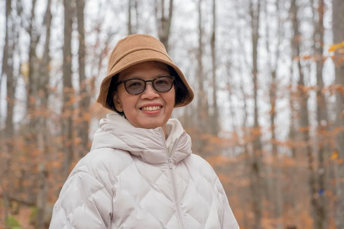 Ảnh minh hoạ — Phụ nữ châu Á trung niên đeo kính, nụ cười ấm áp
