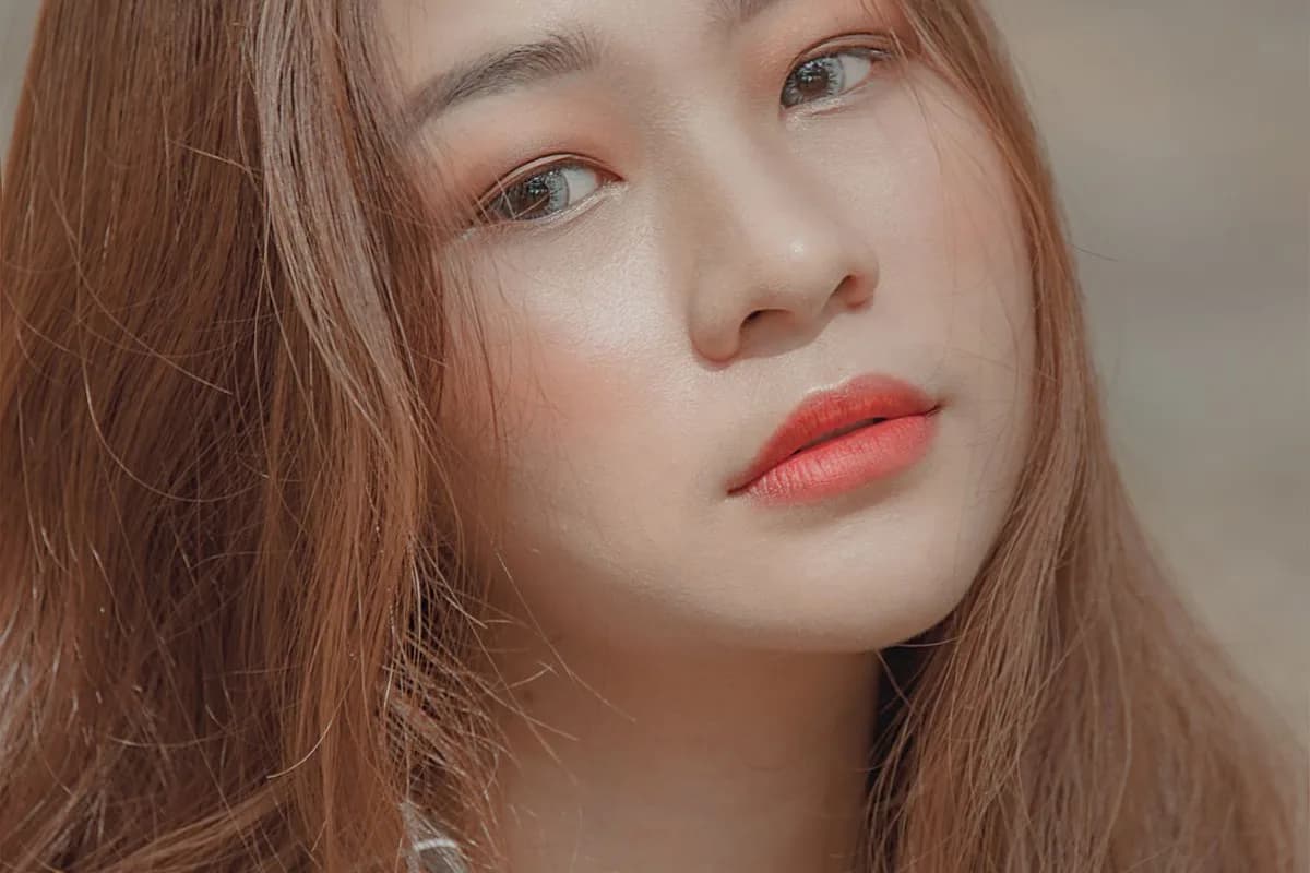 Illustrative image — An Asian woman with brown hair and clearly defined features on a clean neutral background