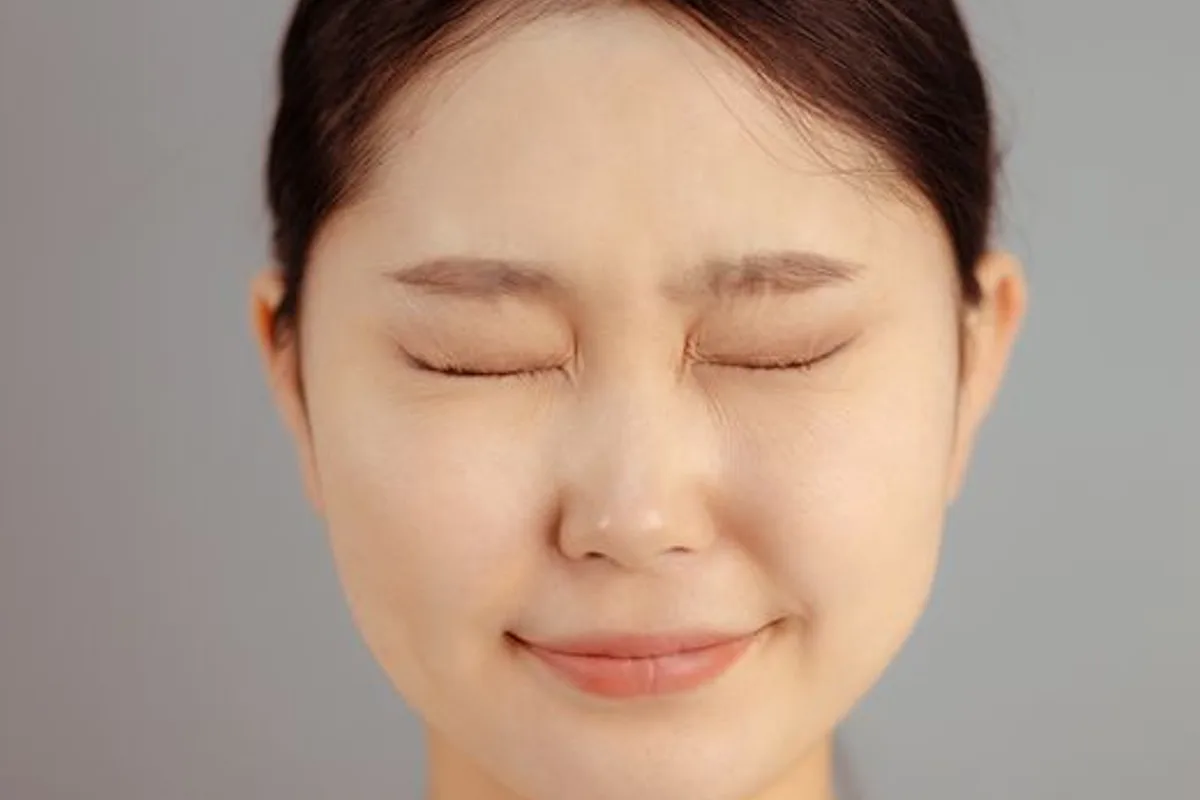 Imagen ilustrativa — Mujer asiática relajada con los ojos cerrados, luciendo una piel natural y suave