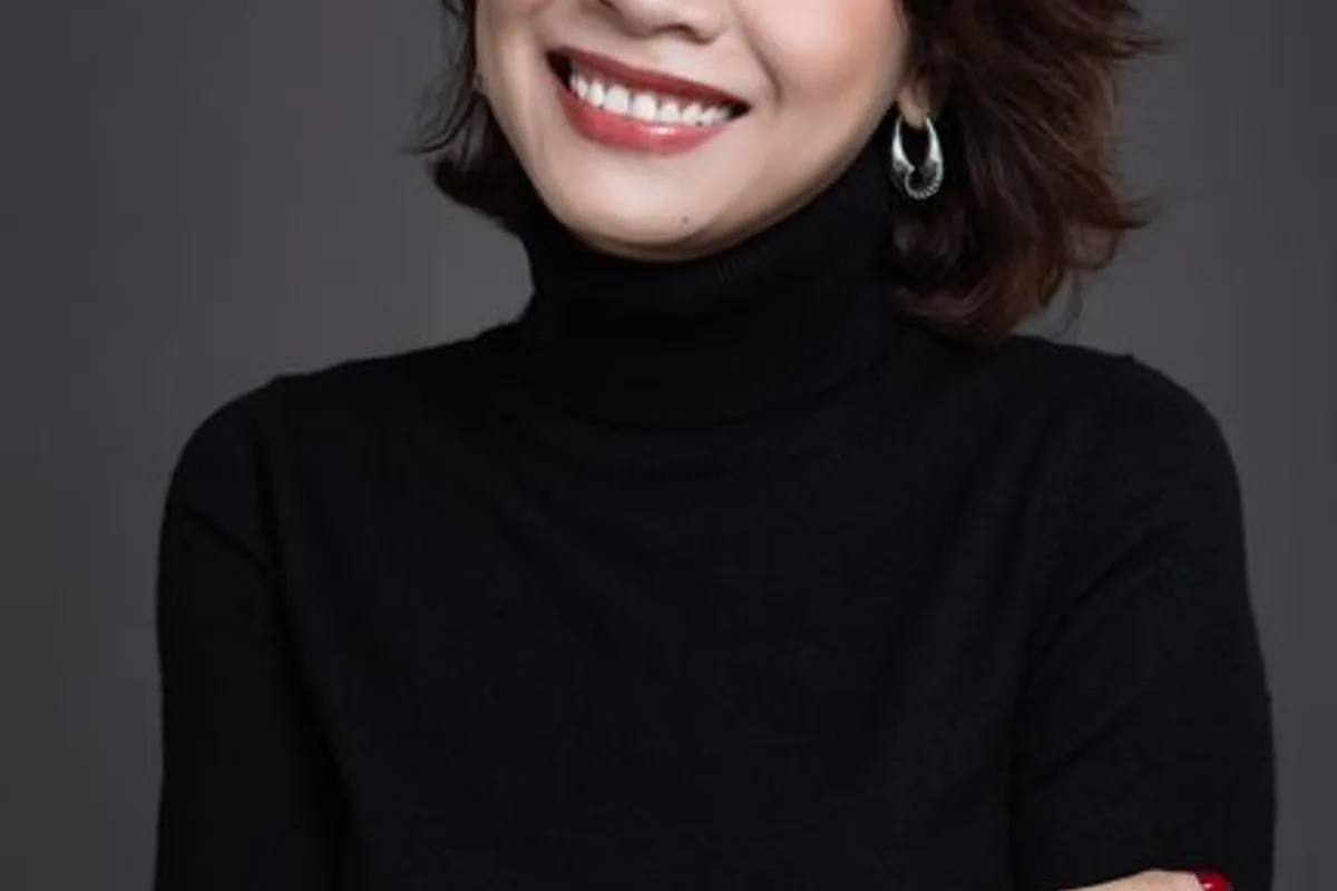 插图 — 身穿黑色高领、微笑抱臂的中年亚洲女性,肤色明亮