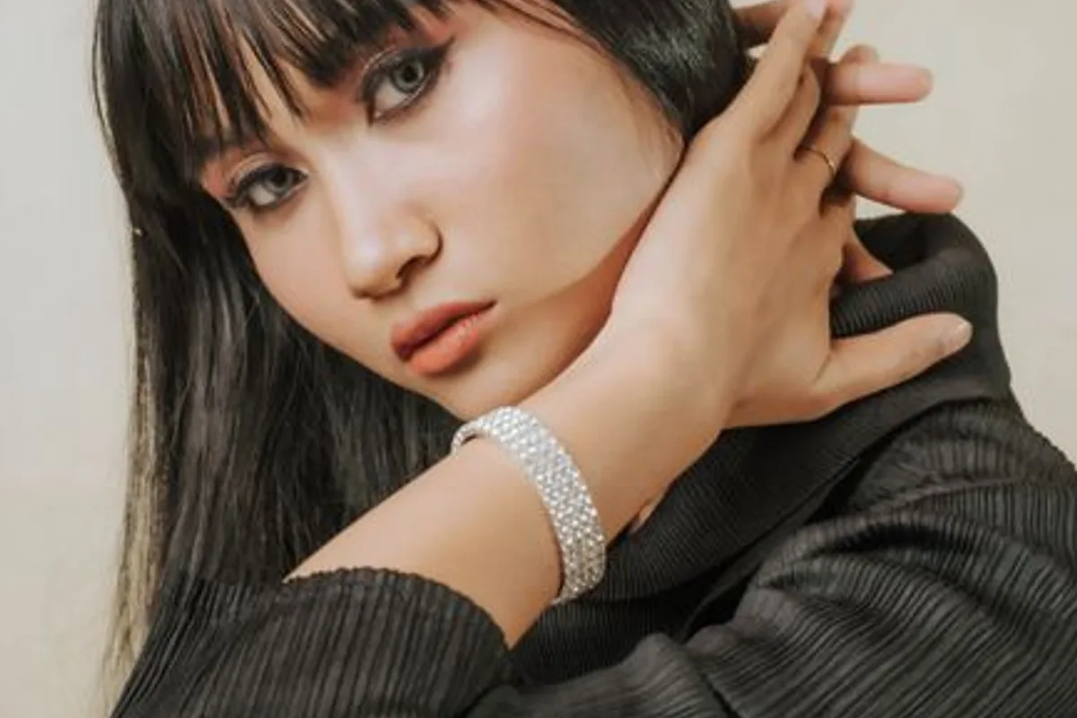 Illustrative image — An Asian woman with blunt bangs in a dark top, a gentle gaze and bare skin
